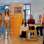 Beatrix Wilkens mit Schülerinnen des Gymnasiums Bruchhausen-Vilsen vor dem RollUp Banner des Projekts Digitale Lernallianz