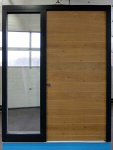 Schlichte und geradlinige Haustür mit schwarzem Rahmen und Naturholzblatt sowie großem seitlichen Glaselement